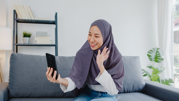une femme musulmane porte le hijab en utilisant un appel vidéo téléphonique parlant avec un couple à la maison.