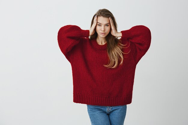 La femme ne peut pas se concentrer sur le travail. Portrait de belle étudiante féminine se tenant la main sur les tempes et regardant avec une expression floue et perdue en se tenant debout.