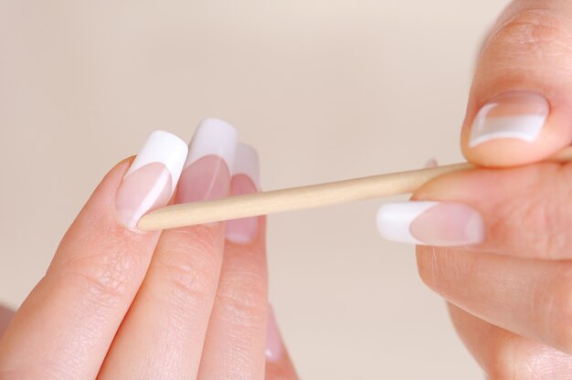 Femme de nettoyage cuticule sur les mains avec un bâton cosmétique