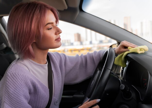 Femme nettoyant le tableau de bord de sa voiture avec un chiffon