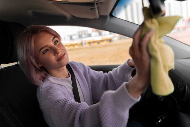 Femme nettoyant le tableau de bord de sa voiture avec un chiffon