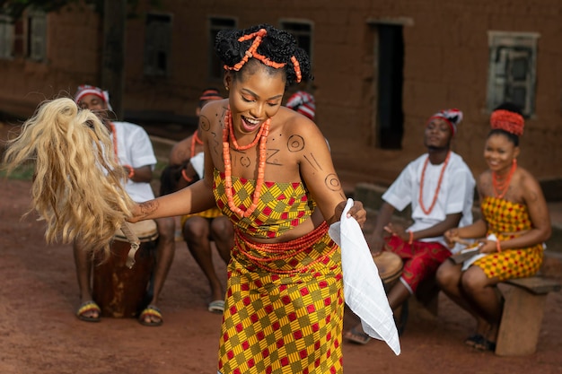 Femme nigériane de coup moyen dansant à l'extérieur