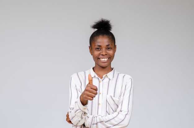 Femme nigériane souriante célébrant le succès avec les pouces vers le haut