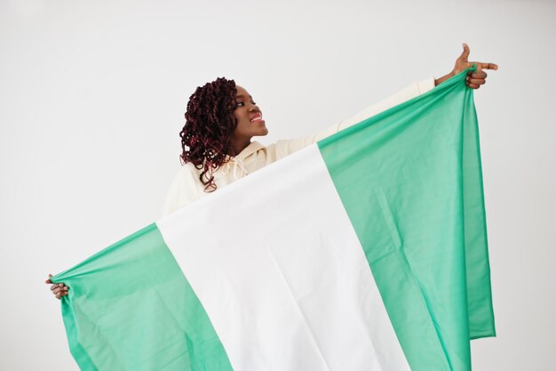 Une femme nigériane tient le drapeau du nigéria isolé sur un mur blanc.