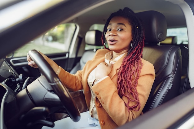 Femme noire émotionnelle assise dans une voiture