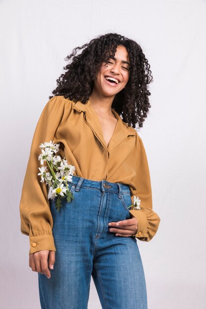 Femme noire avec des fleurs de Marguerite dans la poche d&#39;un jean en riant