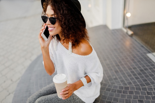 Femme noire réussie, blogueuse ou gérante de magasin parlant par téléphone portable pendant la pause-café.