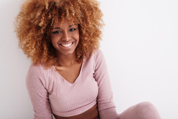 Femme noire souriante aux cheveux bouclés blonds brillants