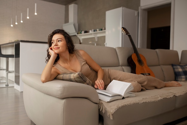 Photo gratuite femme numérique se déconnectant à la maison en lisant un livre