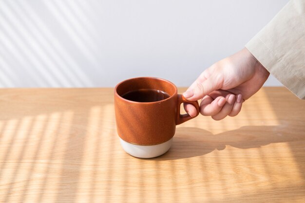 Femme obtenant une tasse de café d'une table en bois