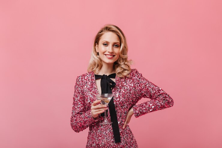 Photo gratuit femme optimiste en robe élégante avec sourire regarde à l'avant et détient un verre à martini
