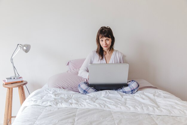 Femme avec un ordinateur portable au lit