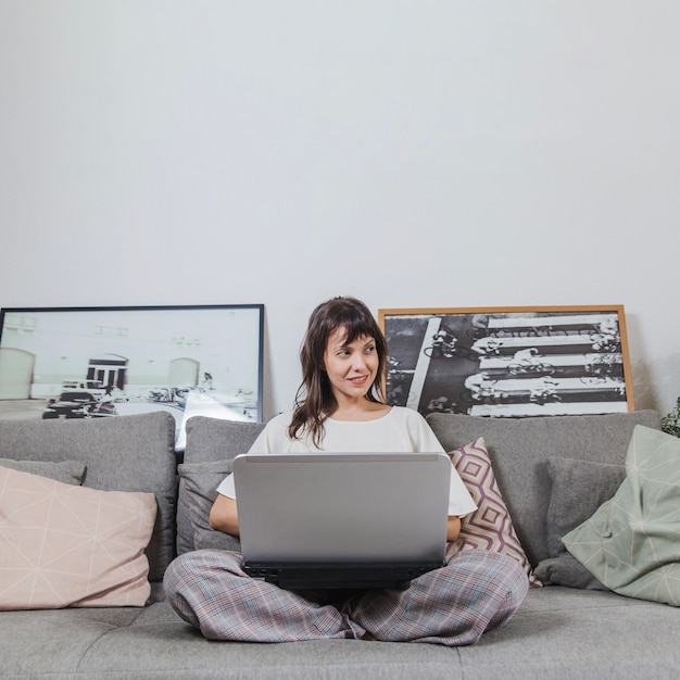 Femme avec un ordinateur portable sur le canapé