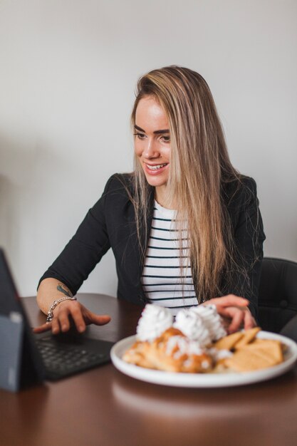 Femme avec ordinateur portable et pâtisserie