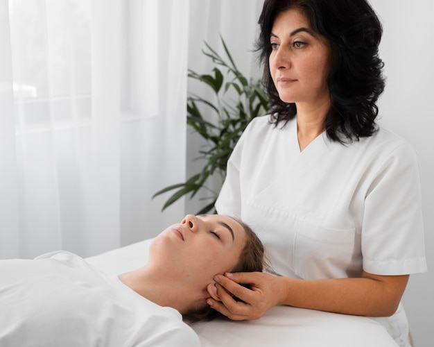 Femme ostéopathe traitant un patient à l'intérieur