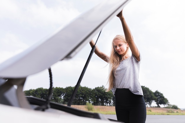 Femme ouvrant le capot de la voiture