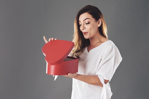 Femme ouvre une boîte en forme de coeur rouge