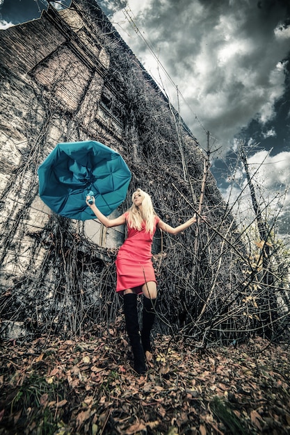 Femme avec un parapluie dans un endroit abandonné