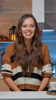 Femme parlant en appel vidéo dans une cuisine décorée à la maison