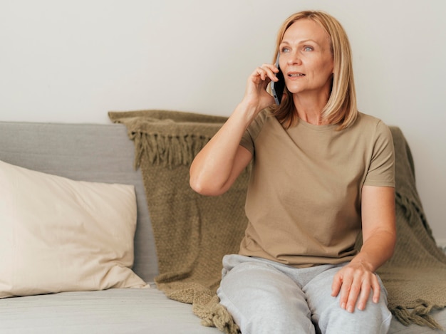Femme parlant au téléphone à la maison pendant la quarantaine