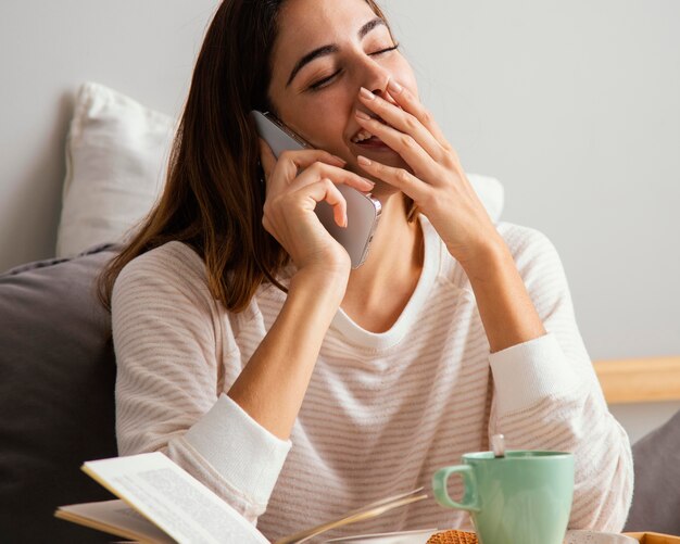 Femme parlant au téléphone et à la maison et en riant