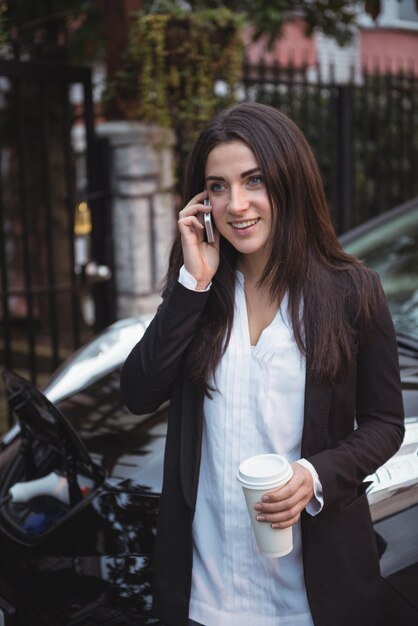 Femme Parlant Au Téléphone Mobile Pendant Que La Voiture Est Chargée