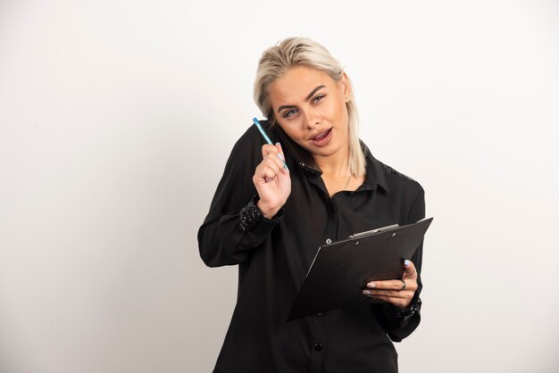 Femme parlant au téléphone mobile et tenant un presse-papiers. Photo de haute qualité