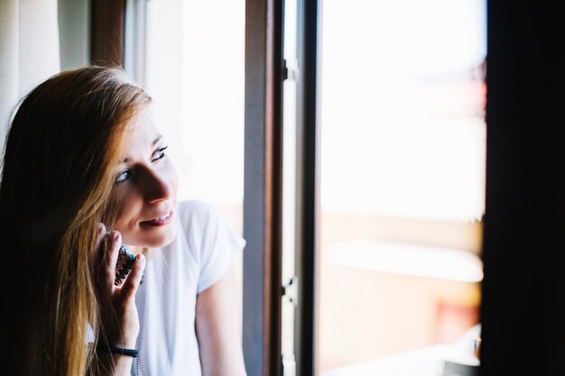 Femme parlant au téléphone près de la fenêtre