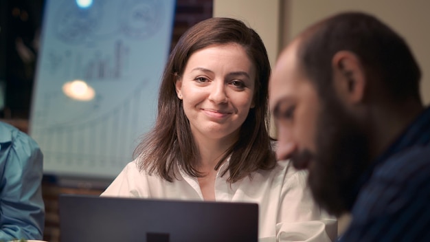 Photo gratuite femme parlant avec un employé en réunion d'affaires, portrait souriant, ralenti. discussion entre collègues, remue-méninges, communication dans un espace de coworking, directeur de bureau regardant la caméra. prise de vue à main levée.