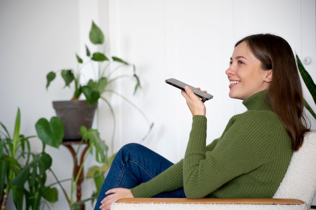 Femme parlant sur son smartphone tout en étant à la maison en utilisant la fonction mains libres