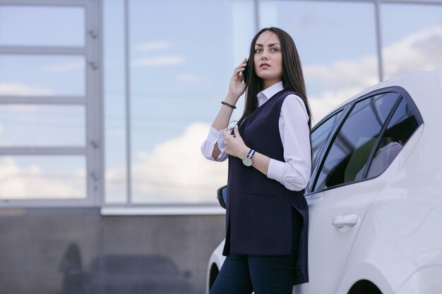 Une femme parle au téléphone avec une voiture blanche