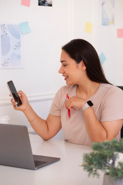 Photo gratuite femme passant un appel vidéo à l'aide d'un ordinateur portable depuis son domicile