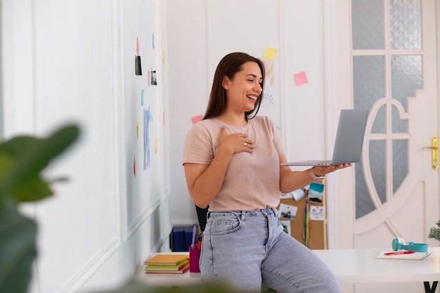 Photo gratuite femme passant un appel vidéo à l'aide d'un ordinateur portable depuis son domicile