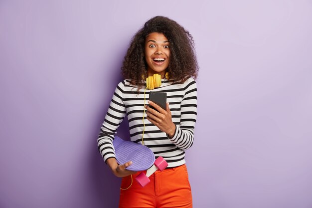 Femme patineuse à la mode posant avec une longue planche