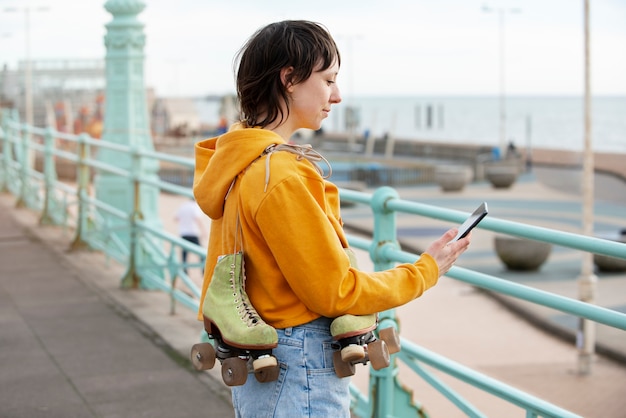 Femme avec des patins à roulettes à l'aide de son smartphone à l'extérieur