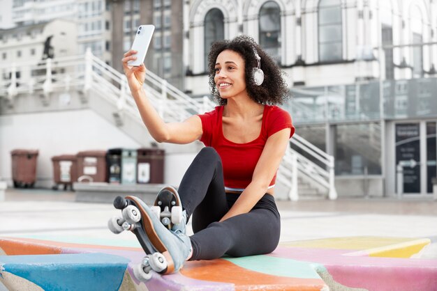 Femme avec des patins à roulettes prenant un selfie à l'extérieur