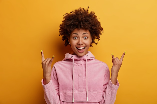 Une femme à la peau foncée positive fait un signe rock et démontre un geste rock-n-roll