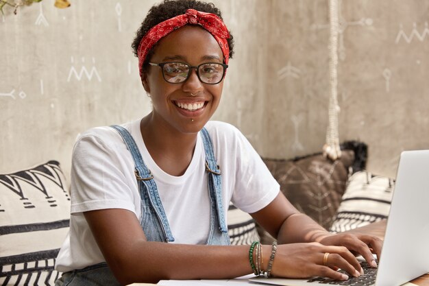 Une femme à la peau foncée positive sourit joyeusement, prépare un horaire de travail pour l'employé