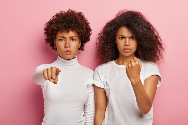 Photo gratuite une femme à la peau foncée stricte pointe vers la caméra et regarde sérieusement