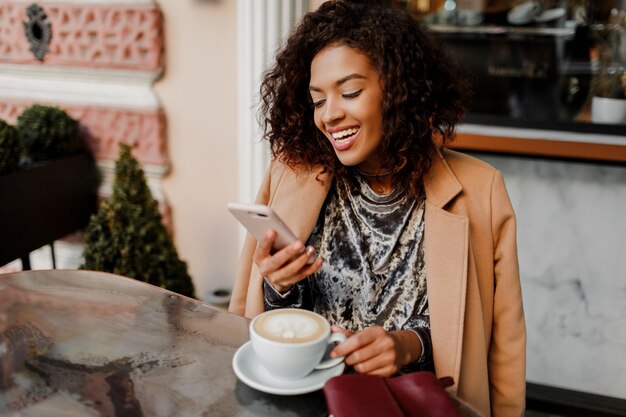 Femme à la peau noire et sourire candide parlant par téléphone