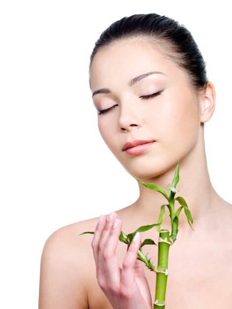 Femme avec une peau propre sur le visage tenant une plante