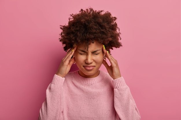 Femme à la peau sombre en détresse frotte les tempes, se sent étourdi et mal de tête sévère