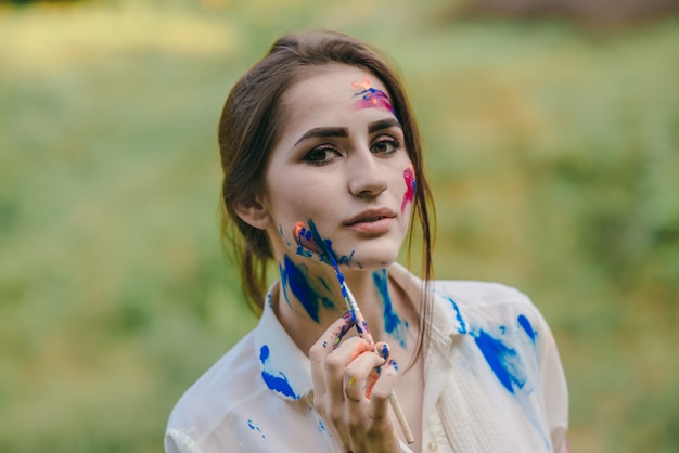 Femme peignant sa joue en bleu avec un pinceau