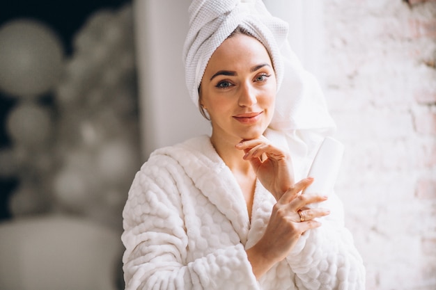 Femme en peignoir avec une lotion pour le corps