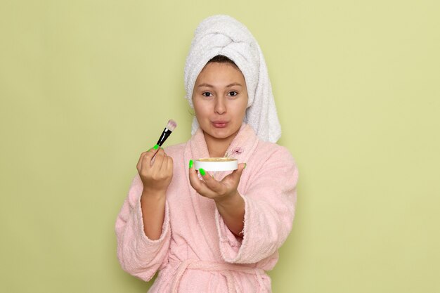 femme en peignoir rose faisant du maquillage