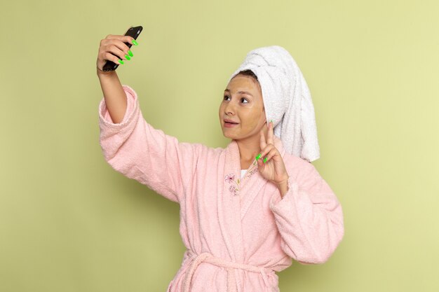 Femme en peignoir rose prenant un selfie