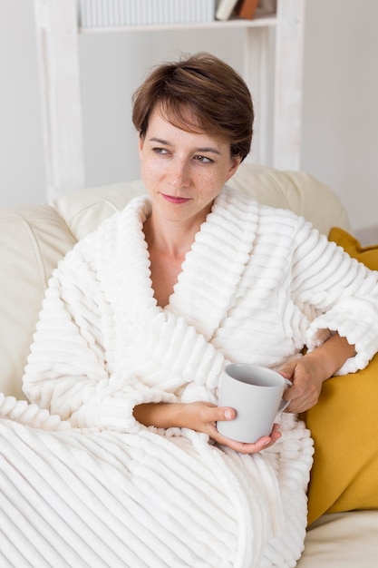 Femme en peignoir tenant une tasse de thé