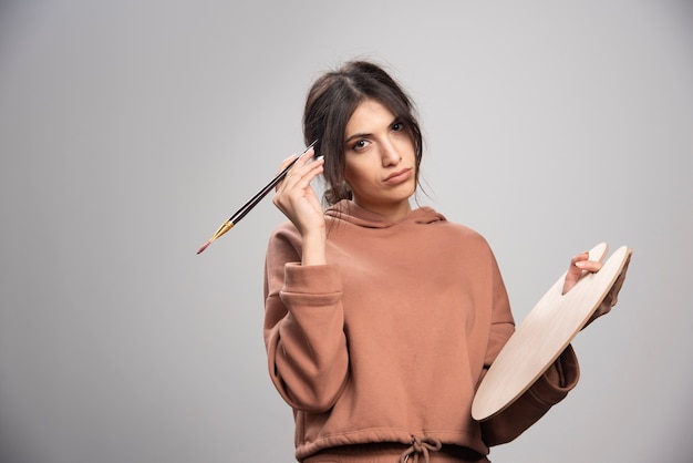 Femme peintre posant avec palette et pinceau de peintre vide