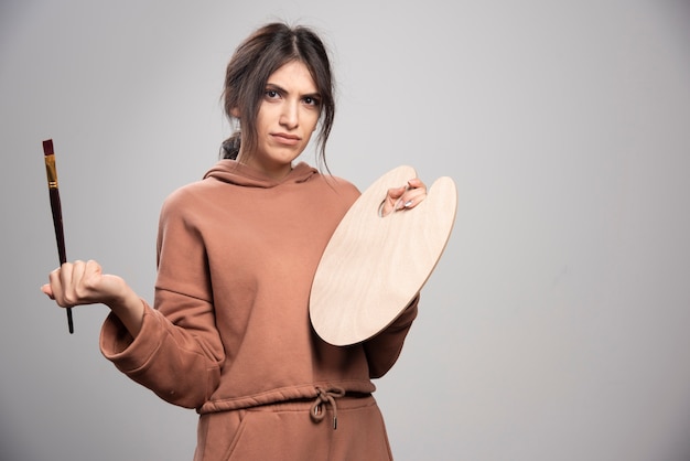 Femme peintre tenant une palette et un pinceau de peintre vide