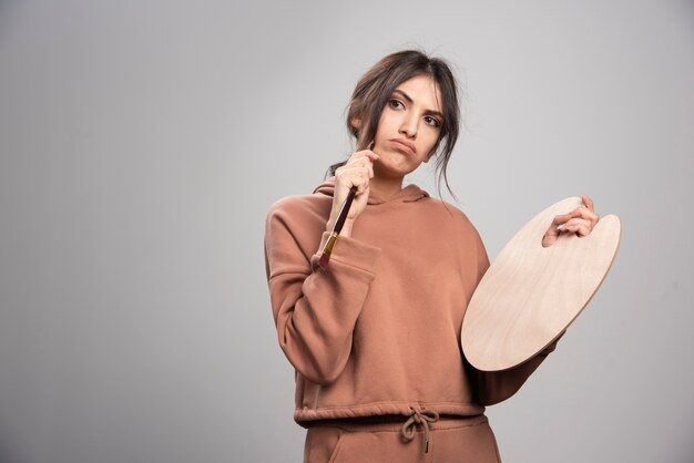 Femme peintre tenant une palette et un pinceau de peintre vide